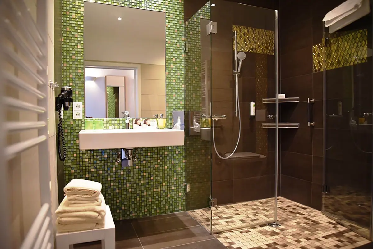 Barrierefreies Bad mit befahrbarer Dusche und grünem Mosaik