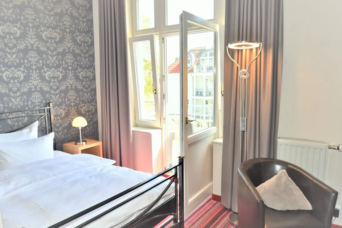 Einzelzimmer mit Metallbett und Sessel