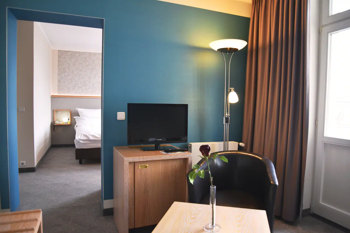 Juniorsuite mit Petrol-Wand und Durchblick in den Schlafbereich
