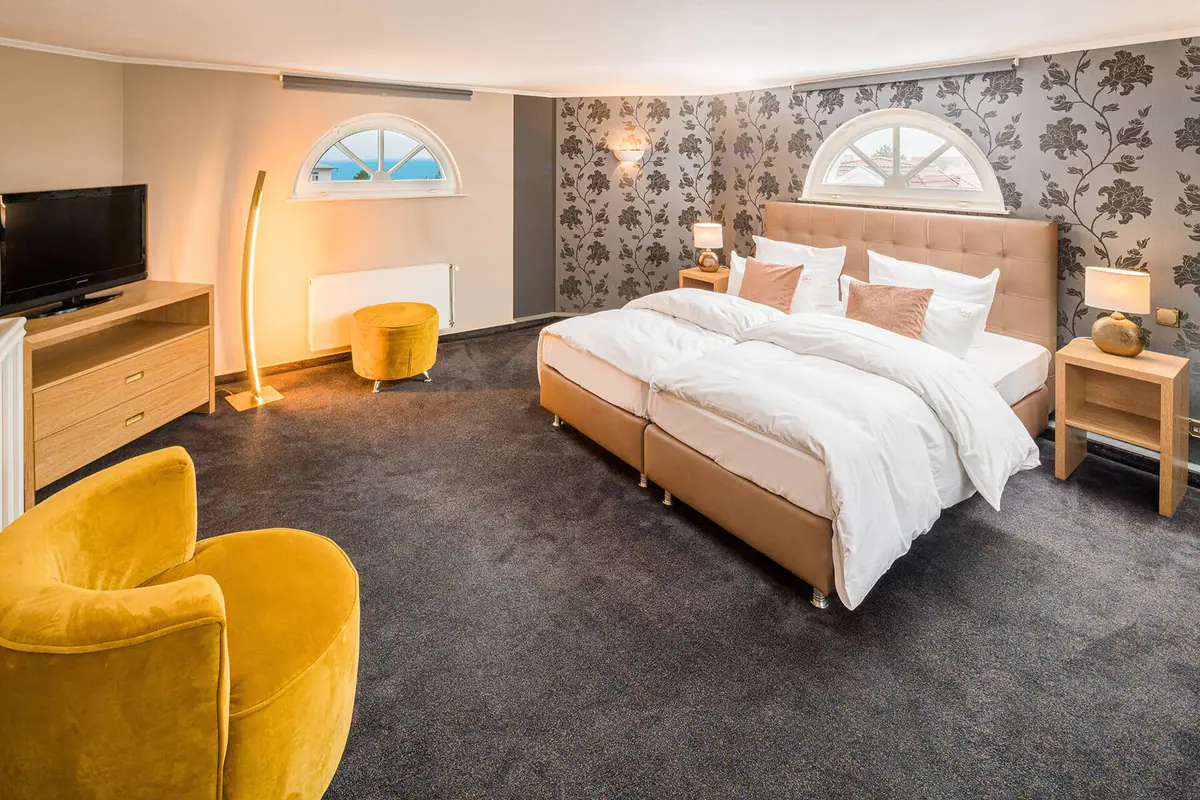 Schlafzimmer der Turmsuite mit gelben Sesseln und Rundbogenfenster